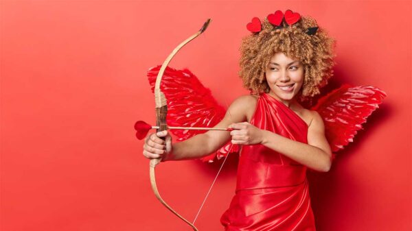 mulher negra vestida de cupido com uma flecha em formato de coração em fundo vermelho