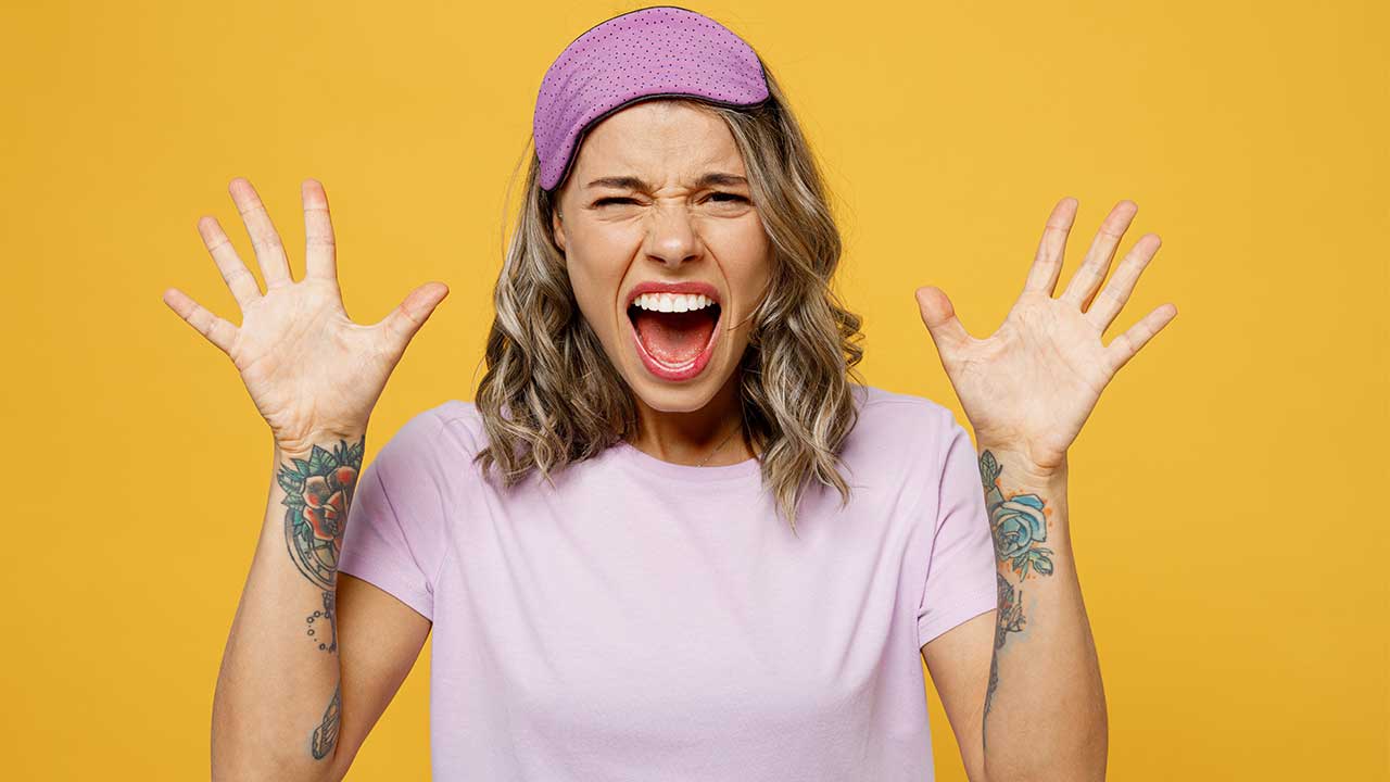 mulher jovem gritando com um tapa olho noturno roxo na testa em fundo amarelo