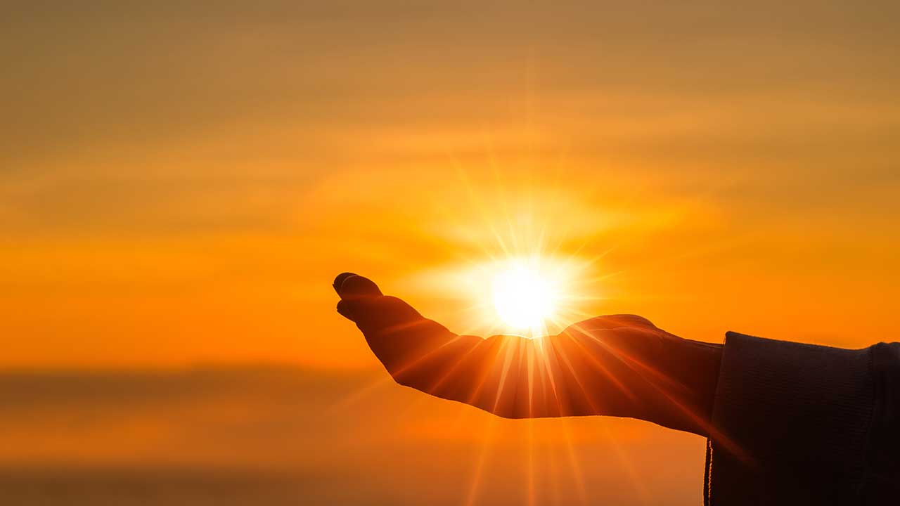 mão esticada ao ar livre na altura do pôr do sol alaranjado