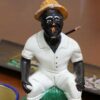 imagem de um preto velho em cima de uma mesa de madeira com um incensário atrás e uma caneca de café na frente