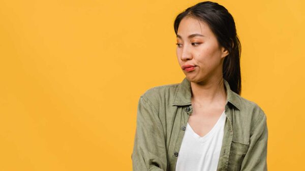 mulher olhando de canto e com cara de incomodada em fundo amarelo
