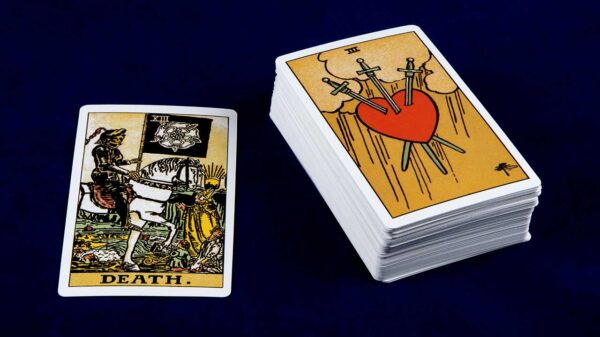 carta a morte do tarot ao lado de um deck de baralho de tarot em um fundo azul marinho